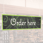 Natural Collection's wayfinding hanging department sign that has "Order Here," digitially printed in white text and on PVC.