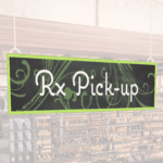 Natural Collection's wayfingding hanging department sign that has "RX Pick-up," digitially printed in white text and on PVC.