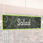 Natural Collection's wayfingding hanging department sign that has "Salad," digitially printed in white text and on PVC.